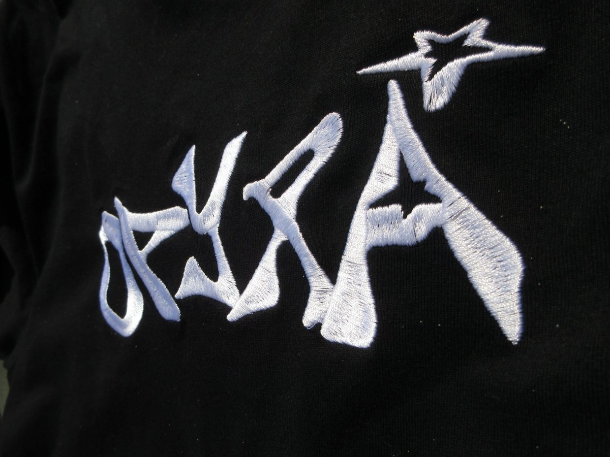 Close-up of the white OPYRA logo embroidered on a black tee